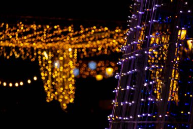 Geceleyin renkli LED ampullerden yapılmış çeşitli şekillerde Noel ışıltısı süslemeleri.