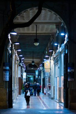 Valencia, İspanya. 23 Ocak 2023 - Şehrin merkezinde bazı geleneksel mağazaları ve işletmeleri olan bir binanın altındaki cadde geçidi ya da kapalı. Gece fotoğrafı.