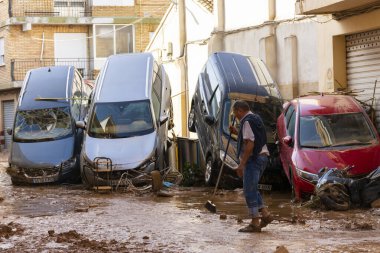 Catarroja, Valencia, İspanya. 31 Ekim 2024 - Son selden sonra, bir komşu evinin önünü temizliyor, hala yığılmış araçlar varken, suyun gücüyle süpürülmüş.