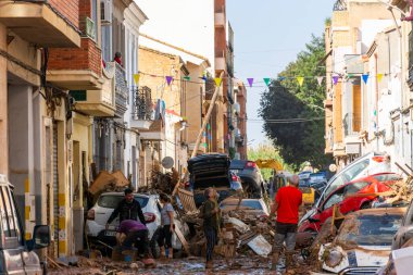 Massanassa, Valencia, İspanya. 31 Ekim 2024 - Bölgedeki sellerin ardından, insanlar temizlik ve enkaz temizleme işlerini yaparken, kasabada yığılmış araçlarla dolu bir cadde ortaya çıktı..