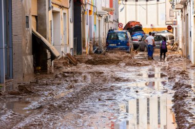 Massanassa, Valencia, İspanya. 31 Ekim 2024 - Selden sonra, insanlar istiflenmiş arabalara bakarken evleri ve caddeleri temizliyorlar