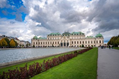 Avusturya, Viyana 'daki Avusturya Belvedere Sarayı' nın nefes kesici manzarası, muhteşem Barok mimarisi ve güzel manzaralı bahçeleri, bulutlu gökyüzüne karşı kurulmuş, bu ikonik simgenin zarafetini artırıyor.