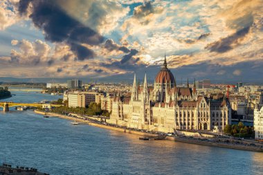 Macaristan Parlamentosu 'nun çarpıcı günbatımı gökyüzü altında nefes kesen manzarası, Budapeşte' nin güzelliğini yansıtıyor. Gündüzün geceye geçişi gibi.