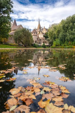 Vajdahunyad Şatosu, Macaristan 'ın Budapeşte kentinin sakin güzelliğini gözler önüne seren, bulutlu bir gökyüzü tarafından çerçevelenmiş, sonbahar yapraklarıyla çevrili küçük bir göle yansıdı.