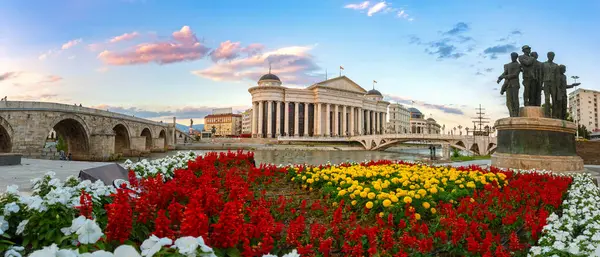 Üsküp şehir merkezinin panoramik manzarası. Arkeoloji Müzesi 'nin önündeki renkli çiçekler. Kuzey Makedonya 'nın başkentinin güzel bahar manzarası. Anıtlara, Taş Köprü 'ye ve Sanat Köprüsü' ne bakın..