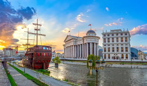 Makedonya Arkeoloji Müzesi, Vardar Nehri 'nde eski bir ahşap gemiyle gün batımında Üsküp' te bulunuyor. Kuzey Makedonya 'nın başkentinin güzel bahar manzarası.