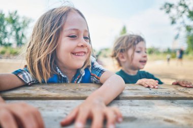 Two little boys are relaxing at a picnic table on a summer day                      