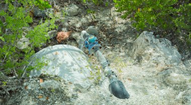 closeup detailed view of an old concrete,plastic water communication pipes in the bushes summer sunny day clipart