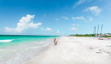 Küba, Varadero plajı, güzel davetkar bir okyanus manzarası, kumsalda güneşli ve güneşli bir günde kumsalda gezen bir insan. 