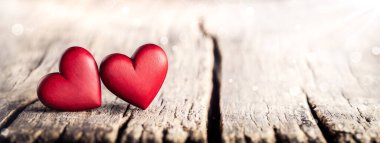 Güneş ışığı ve Bokeh Sevgililer Günü 'nde Kırsal Masada İki Kırmızı El Ahşap Kalpler Oluşturdu 