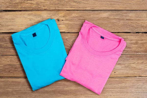 Blue and pink cotton T-shirt put on wooden floor background.
