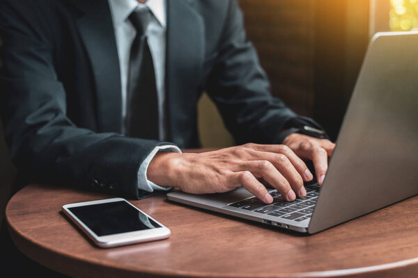 Businessman using his laptop while working in the office, business people working with laptop in office, Notebook laptop on wood table, business concept