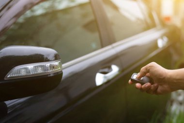 Arabayı tutan ve uzaktan kumandayı iten adam arabanın kilidini ya da kilidini açar.