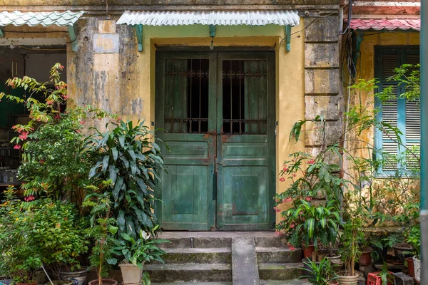 Hanoi, Vietnam - 4 Haziran 2022: Eski sarı bir evin ana kapısı önü saksılarla dolu ve hiç insan yok