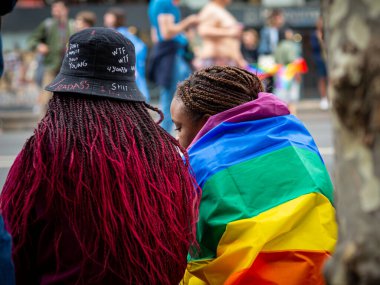 2022 'de Paris' te iki genç siyah kadın sırtında gökkuşağı bayrağı taşıyan bir gay gururu görülüyordu.