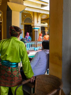 Medan, Endonezya - 21 Temmuz 2022: Geleneksel giysiler giymiş iki adam tarafından izlenen dört aktör geleneksel giysiler içinde gösteri yapıyor. Bulutlu bir günde çekildi.