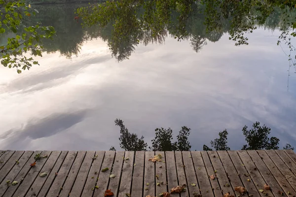 Drewniany Pokład Widokiem Spokojną Rzekę Drzewami Odbitymi Wody Zabrany Częściowo — Zdjęcie stockowe
