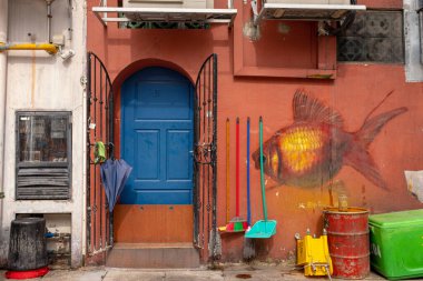 Kampong Glam, Singapur - 19 Aralık 2022: Kampong Glam 'ın arka sokaklarının anonim sanat eserleri, kırmızı boyalı bir duvara karşı insansız bir Japon balığını temsil ediyor.