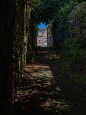 Quintin, Brittany, Fransa 'da güneşli bir yaz gününde insanların olmadığı dar, karanlık bir ara sokak.