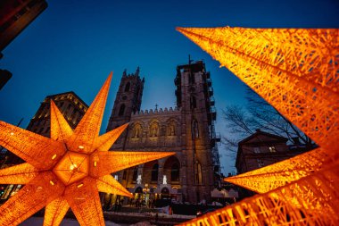 Montreal, Quebec, Kanada - 26 Şubat 2023: Notre-Dame Bazilikası iç karartıcı bir kış akşamında dekoratif turuncu ışıklar ve ön planda tanınmayan bazı insanlarla çekildi