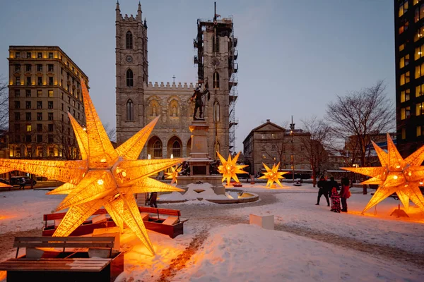 Montreal, Quebec, Kanada - 26 Şubat 2023: Notre-Dame Bazilikası, iç karartıcı bir kış akşamı dekoratif sarı ışık ve bazı tanınmayan insanlarla ön planda çekildi