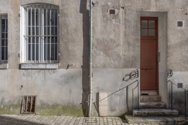 Kırmızı giriş kapısı olan eski bir Fransız evinin ön cephesi. Güneşli bir yaz akşamında gölgeli ve insan olmadan çekilmiş..