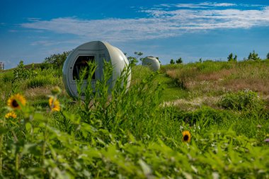 Rehabilite edilmiş bir çöp sahasının tepesinde gaz menfezini saklayan küresel bir yapı. Güneşli bir yaz gününde Montreal, Kanada 'daki Frederic Back parkında çekildi.