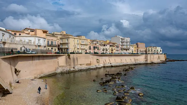 Siraküza kıyısı, Sicilya, İtalya. Fırtınalı bir kış gökyüzü altında tanınmayan insanlar tarafından çekildi..