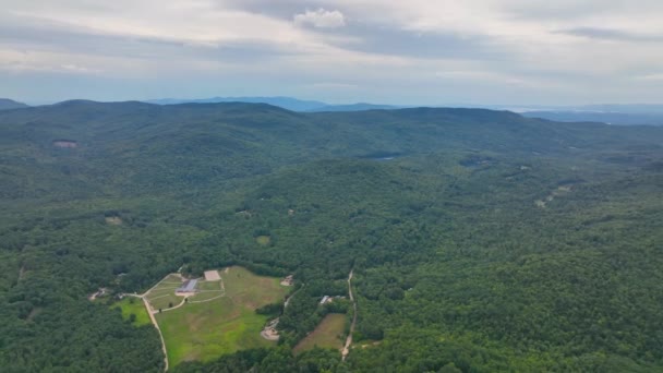 ニューハンプシャー州キャンプトンの町の背景にあるホワイトマウンテン国立の森と夏のキャンプトン山を飛ぶ — ストック動画