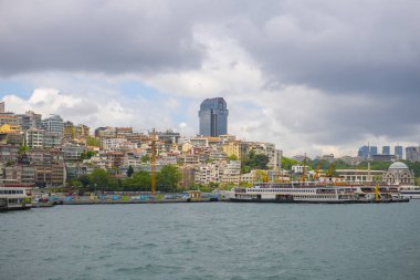 Türkiye 'nin tarihi İstanbul kenti Beyoğlu' nun Beyoğlu ilçesine bağlı Boğaziçi limanındaki Suzer Plaza binası ile Kabatas limanındaki feribot gemisi ve tarihi liman binası. 