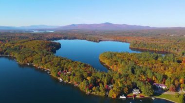 Sonbaharda Wolfeboro, New Hampshire NH, ABD 'de arka planda Ossipee Dağları ile Winnipesaukee Gölü' nde Ayna Gölü sahili manzarası. 