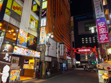 Shops and restaurants at night on Kabukicho Ichiban Gai Street in Shinjuku, Tokyo, Japan.  clipart