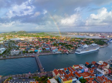 Koningin Emmabrug yüzer köprü görüntüsü Punda ve Otrobanda 'yı birbirine bağlar, arka planda Willemstad, Curacao' da gökkuşağı vardır. Tarihi Willemstad UNESCO 'nun Dünya Mirası Bölgesi. 