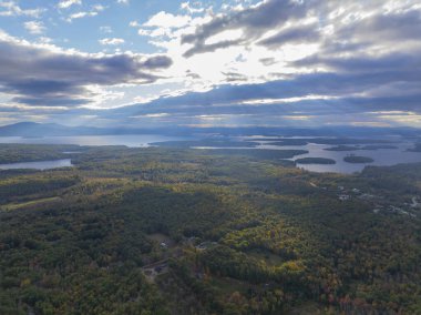 Winnipesaukee Gölü 'nün sonbaharda New Hampshire NH, ABD' deki Tuftonboro kasabasından gelen bulutların arasından geçen güneşli havadan görüntüsü.. 