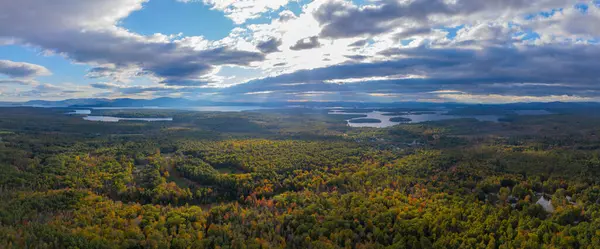 Winnipesaukee Gölü 'nün sonbaharda New Hampshire NH, ABD' deki Tuftonboro kasabasından gelen bulutların arasından geçen güneşli havadan görüntüsü.. 