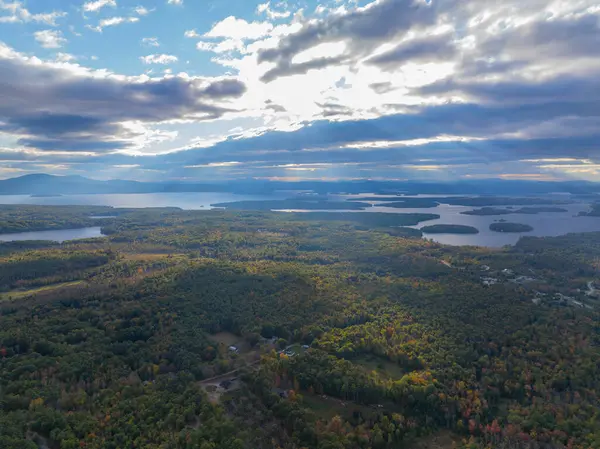 Winnipesaukee Gölü 'nün sonbaharda New Hampshire NH, ABD' deki Tuftonboro kasabasından gelen bulutların arasından geçen güneşli havadan görüntüsü.. 