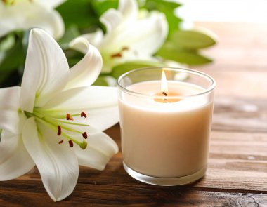 Tahta masanın üzerinde beyaz zambak çiçekleri olan bir mum. ai oluşturuldu