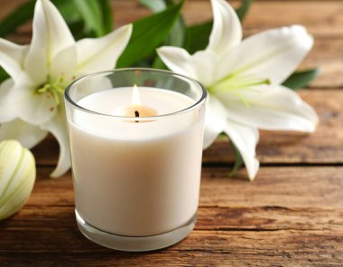 Kırsal bir ahşap Hawaii 'de yeni açmış nilüferlerin olduğu bir vazonun yanında, yumuşak parlayan bir mum.