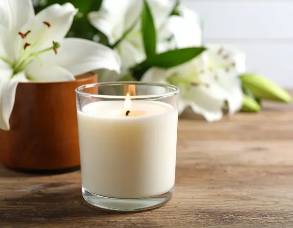 Kırsal bir ahşap Hawaii 'de yeni açmış nilüferlerin olduğu bir vazonun yanında, yumuşak parlayan bir mum.