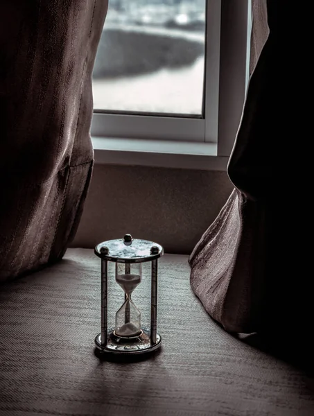 銀製の砂時計や砂時計は 美しいカーテンを通して初期の光と部屋のガラス窓に配置されています 光と希望と時間の価値の概念 テキスト フォーカス ぼかしのためのスペース — ストック写真