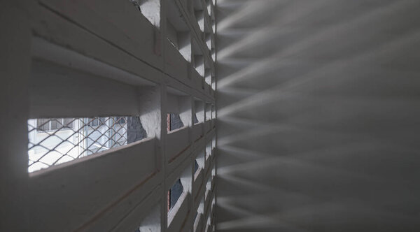 The sunlight shines through light channels wall of old gymnasium. Concrete walls have holes for sunlight to penetrate through the holes from the outside, Light and shadow concept, Space for text, Selective Focus.