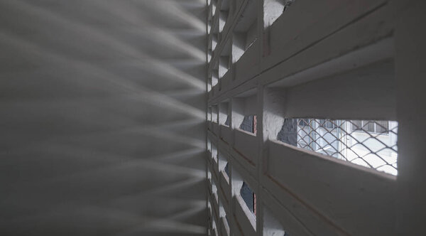 The sunlight shines through light channels wall of old gymnasium. Concrete walls have holes for sunlight to penetrate through the holes from the outside, Light and shadow concept, Space for text, Selective Focus.
