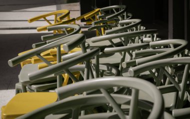 Koyu yeşil yığını (haki rengi) ve sarı plastik sandalyelerin ayrıntıları güneşli bir günde kafe terasının yanındadır. Metin için boşluk, Seçici odak.