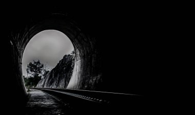 Demiryolu tünelinin içinde ve demiryollarının sonunda doğal ışık var. Tünelin sonundaki ışık, ışıklar ve gölgeler, hedeflerine ulaşma kavramı, uzayı kopyalama, özellikle odak yok,.