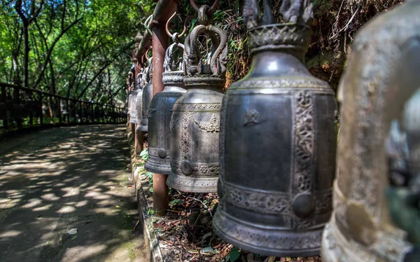 Many metallic bells hanging in a row on wooden pillars outside in thai buddhist temple. Lined with many beautiful bells, Thai temple bell which believe that who knock this bell will get the good luck, Image with shallow depth of field,  No focus, spe