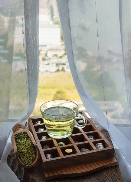 Refreshing and Enjoy with A cup of hot hemp tea (CBD herbal tea) and Dried organic hemp leaves on Vintage thimbles collection placed on an Old wooden box on old rustic wooden table by the window view with sunlight. Healthy drink concept. Space for te