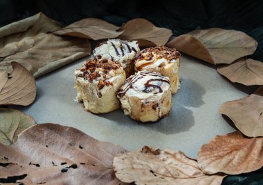 İki tane krem peynirli kremalı çörek ve iki tane karamelli fındıklı krema ve seramik tepside fındıklı. Lezzetli yemek kavramı, Seçici Odaklanma.