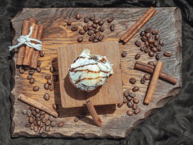 Çikolata (yumuşak çikolatalı çörek) üzerinde krem peynirli krema ve üzerinde koyu arkaplan üzerine kahve çekirdekleri olan tarçınlı kahve. Üst Görünüm, Seçici Odaklanma.
