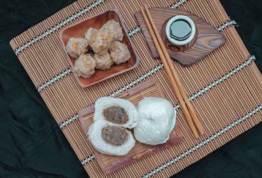 Steamed buns with minced pork filling and Pork shumai or Chinese steamed dumpling served with sour sauce and wooden chopstick. Chinese Dim Sum. Top view, Space for text, Selective Focus.