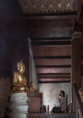 Phetchaburi, Tayland - 14 Mayıs 2022: Wat yai suwannaram tapınağındaki şapelde Phra Phuttha Chinnarat 'a saygılarını sunan genç kadın. Dua et, seçici odaklan..